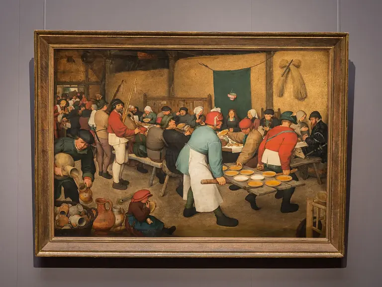 Das Bild zeigt eine große Gruppe von Menschen in einem Raum, die an Tischen sitzen und essen. Einige Personen stehen und servieren Essen. Die Atmosphäre wirkt gesellig und lebhaft, während verschiedene Charaktere in traditionellen Kleidungen miteinander interagieren.