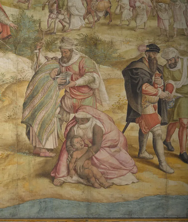 A historical scene depicting several figures, including a woman holding a child, dressed in colorful clothing. Surrounding them are men in various outfits, engaged in a gathering or celebration, set against a natural landscape with trees in the background.